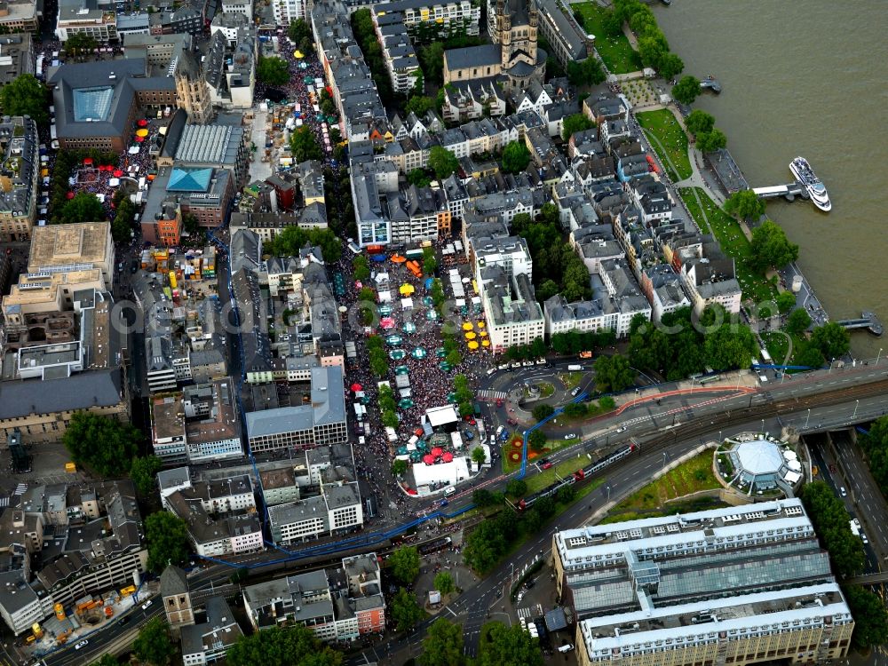 Köln from the bird's eye view: The church Groß St. Martin at the Rhine riverbank in Cologne in the state of North Rhine-Westphalia. The church is one of twelve large romanic churches in the historic city center. It is closely surrounded by history influenced residential and business buildings of the 1970s and 1980s. Large groups of people move through the city center on Christopher Street Day