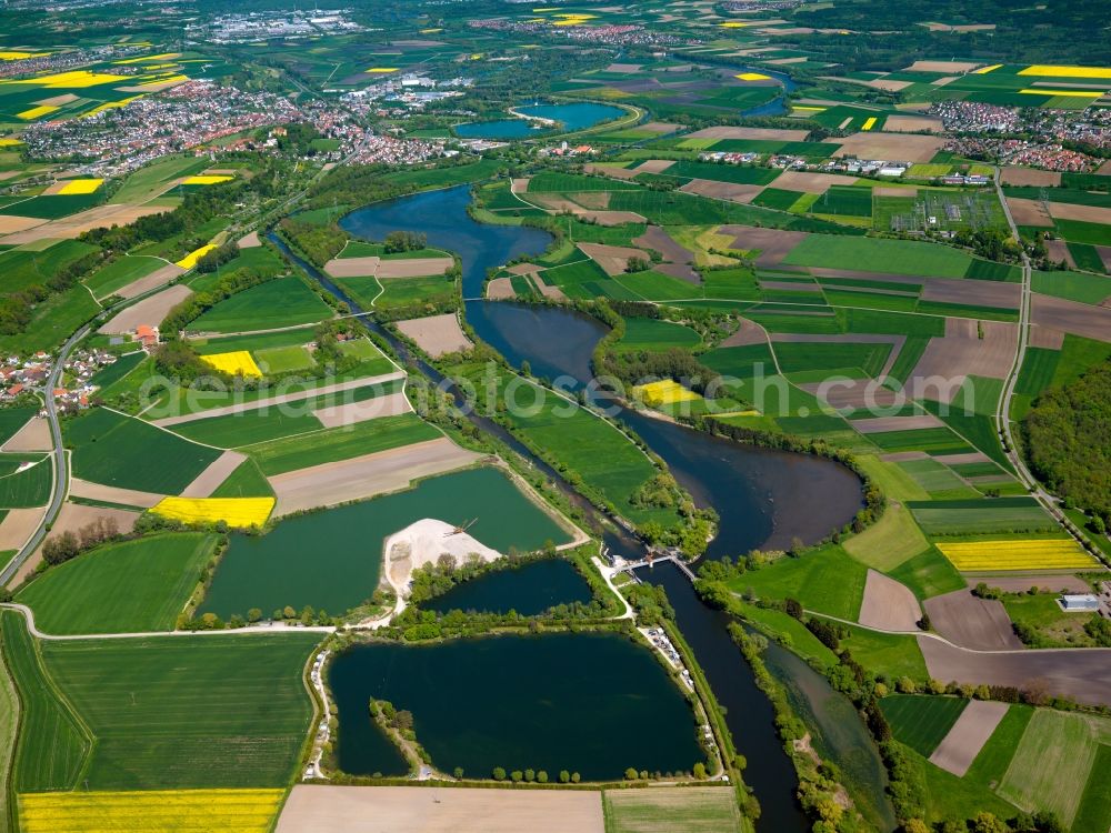 Erbach an der Donau from above - The quarry ponds and the water power station Ersingen in the Donaurieden part of the town of Erbach on Danube in the state of Baden-Württemberg. The river runs narrowly between fields and small towns. The landscape is characterised by waters along the Danube riverbank. The hydro power station forms a bridge on an older part of the river. Right next to it are three artificial quarry ponds