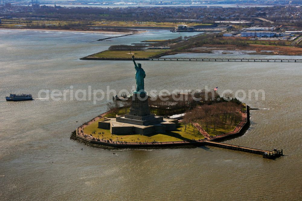 Aerial photograph New York - Die Freiheitsstatue ist eine von Frédéric-Auguste Bartholdi geschaffene neoklassizistische Kolossalstatue bei New York. Sie steht auf Liberty Island im New Yorker Hafen und wurde am 28. Oktober 1886 eingeweiht. Die Statue ist seit 1984 als Weltkulturerbe der UNESCO klassifiziert. Die Statue stellt die in Roben gehüllte Figur der Libertas, der römischen Göttin der Freiheit, dar. / The Statue of Liberty is a statue created by Frédéric-Auguste Bartholdi. It stands on Liberty Iceland in the New York harbor, and was inaugurated in October 1886. The statue has been classified since 1984 as a World Heritage Site by UNESCO. The statue represents the figure of Libertas, the Roman goddess of freedom.