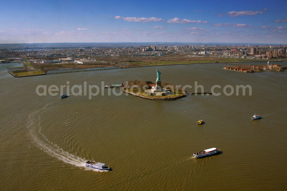 New York from above - Die Freiheitsstatue ist eine von Frédéric-Auguste Bartholdi geschaffene neoklassizistische Kolossalstatue bei New York. Sie steht auf Liberty Island im New Yorker Hafen und wurde am 28. Oktober 1886 eingeweiht. Die Statue ist seit 1984 als Weltkulturerbe der UNESCO klassifiziert. Die Statue stellt die in Roben gehüllte Figur der Libertas, der römischen Göttin der Freiheit, dar. / The Statue of Liberty is a statue created by Frédéric-Auguste Bartholdi. It stands on Liberty Iceland in the New York harbor, and was inaugurated in October 1886. The statue has been classified since 1984 as a World Heritage Site by UNESCO. The statue represents the figure of Libertas, the Roman goddess of freedom.