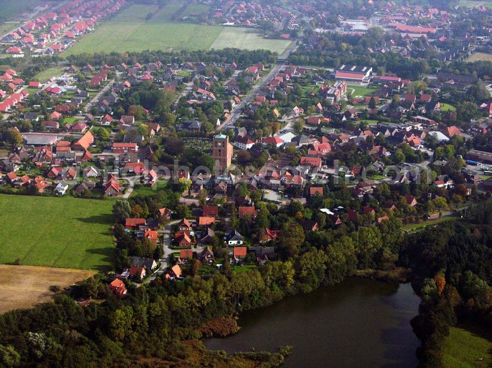 Marienhafe from the bird's eye view: 18.10.2005 Marienhafe; Marienhafe ist eine Gemeinde, zugleich Flecken, und Verwaltungssitz in der Samtgemeinde Brookmerland im Landkreis Aurich in Ostfriesland. Die Gemeinde hatte 2004 etwa 1.900 Einwohner und erstreckt sich auf einer Fläche von 4,06 Quadratkilometern. Marienhafe ist damit eine der kleinsten Gemeinden in Niedersachsen. Marienhafe hat mehrere Sehenswürdigkeiten und Wahrzeichen zu bieten. Das bekannteste ist sicherlich die St. Marienkirche mit dem Störtebekerturm. Die Kirche wurde in der Mitte des 13. Jahrhunderts als dreischiffige, gewölbte Kreuzbasilika erbaut.