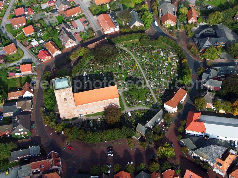 Aerial image Marienhafe - 18.10.2005 Marienhafe; Marienhafe ist eine Gemeinde, zugleich Flecken, und Verwaltungssitz in der Samtgemeinde Brookmerland im Landkreis Aurich in Ostfriesland. Die Gemeinde hatte 2004 etwa 1.900 Einwohner und erstreckt sich auf einer Fläche von 4,06 Quadratkilometern. Marienhafe ist damit eine der kleinsten Gemeinden in Niedersachsen. Marienhafe hat mehrere Sehenswürdigkeiten und Wahrzeichen zu bieten. Das bekannteste ist sicherlich die St. Marienkirche mit dem Störtebekerturm. Die Kirche wurde in der Mitte des 13. Jahrhunderts als dreischiffige, gewölbte Kreuzbasilika erbaut.