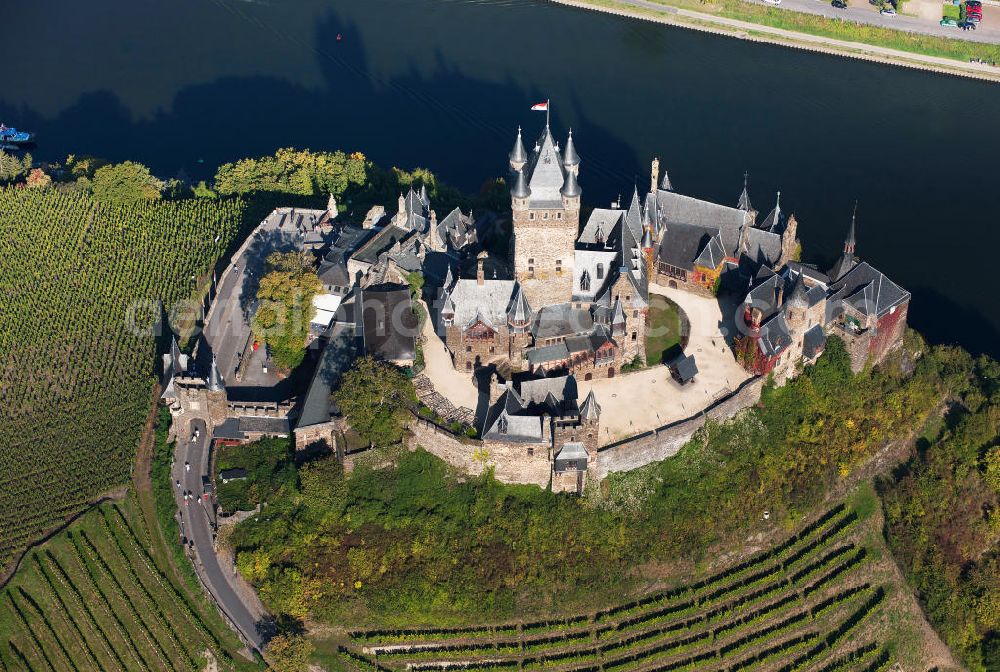 Cochem from the bird's eye view: The Cochem Castle is a castle at the Mosel river in the Rhineland-Palatinate town of Cochem. After it had been destroyed in the 17th century, the businessman Louis Frédéric Jacques Ravené rebuilt the castle according to the taste of romanticism between 1868 to 1877. Today the castle is a museum and event space. The castle hill is used for winegrowing