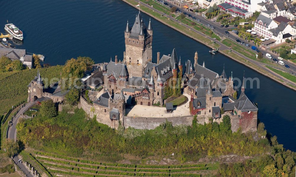 Cochem from the bird's eye view: The Cochem Castle is a castle at the Mosel river in the Rhineland-Palatinate town of Cochem. After it had been destroyed in the 17th century, the businessman Louis Frédéric Jacques Ravené rebuilt the castle according to the taste of romanticism between 1868 to 1877. Today the castle is a museum and event space. The castle hill is used for winegrowing