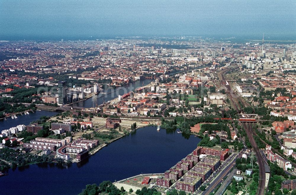 Aerial image Berlin - There is the Rummelsburger bay and the Strahlau peninsula at the municipality border of Lichtenberg, Friedrichshain, Treptow and Kreuzberg. In recent decades created here with the watercity Rummelsburg and the new buildings in Old Strahlau atractive living residences near water. The condominiums are conveniently located by the quick links to the transport hub east cross. Right on the Elsenbruecke rises with the Treptower one of the tallest buildings in Berlin. Only a short drive away is the City-East with the TV tower. The abandoned industrial building of the glass factory Strahlau waiting for a new utilization concept. in the state