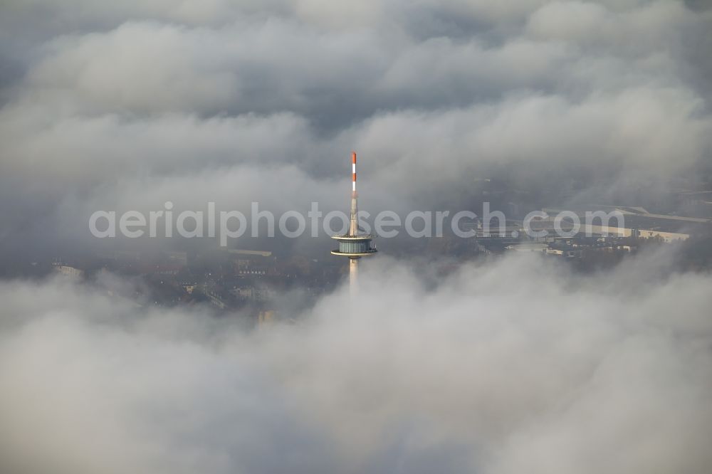 Essen from the bird's eye view: View of the top of the telecommunication tower breaking through an impressive blanket of clouds over the city center of Essen in the state North Rhine-Westphalia. The autumn weather clouds are surrounding the television tower at its location in the Holsterhausen district and form a cloud bank over the Ruhr region city