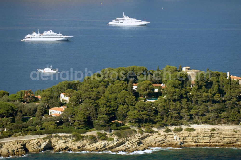 Saint-Jean-Cap-Ferrat from above - Blick auf die Spitze Saint Hospice der Halbinsel Saint-Jean-Cap-Ferrat. Das Cap Ferrat ist eine Halbinsel an der Cote d'Azur. Sie liegt zwischen Nizza und Monaco. Es trennt Beaulieu-sur-Mer und Villefranche-sur-Mer. Der Ort Saint-Jean-Cap-Ferrat erstreckt sich an seinem Ostufer. Die ganze Halbinsel kann auf einem Fußweg umrundet werden. An ihrer Spitze steht ein Leuchtturm als Hafenwegweiser.