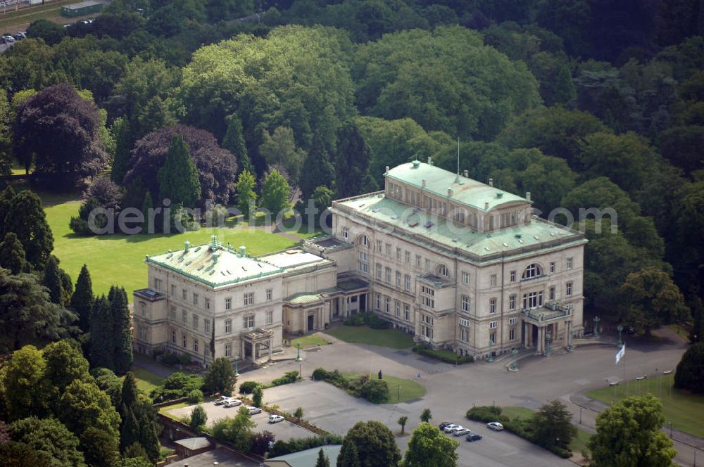 ESSEN from the bird's eye view: Die Villa Hügel, im Essener Stadtteil Bredeney gelegen, wurde 1873 von Alfred Krupp errichtet und ist das ehemalige Wohn- und Repräsentationshaus der Industriellenfamilie Krupp. Die Villa hat 269 Räume, 8100 m² Wohn- und Nutzfläche und liegt in einem 28 Hektar großen Park an prominenter Stelle über dem Ruhrtal und dem Baldeneysee. Verwaltet wird sie heute durch die Kulturstiftung Ruhr, welche regelmäßig Veranstaltungen wie Konzerte oder Ausstellungen dort durchführt. Außerhalb dieser Zeiten kann sie in den Öffnungszeiten besichtigt werden.Die Entstehung der Villa Hügel geht einher mit den Veränderungen in der Friedrich Krupp AG. 1862 wurde durch Alfred Krupp die Prokura eingeführt. Er beabsichtigte damit seine Rolle in der stark gewachsenen Firma auf die strategischen Entscheidungen und die Aufsichtsfunktion zu beschränken. War es bis dato üblich, auf dem Firmengelände zu leben, spiegelt sich dieser „Rückzug“ auch in der Verlagerung des Wohnsitzes der Familie wieder. Im Herbst 1863 besichtigte Krupp das heutige Gelände der Villa und entschloss sich im Januar 1864 soviel wie möglich des damaligen Gutes Klosterbuschhof zu erwerben. Um den Umzug zu beschleunigen, wurde zunächst der Klosterbuschhof um einen Turm erweitert und zu einer Villa umgebaut. Erste Skizzen des Baues wurden von Krupp selbst entworfen und dem firmeninternen Baubüro, zunächst unter der Leitung von Ferdinand Barchewitz, ab 1863 unter der Leitung von Gustav Kraemer, zur weiteren Bearbeitung vorgelegt. Barchewitz fertigte, nachdem Kraemer die Leitung des Baubüros übernommen hatte, Pläne nach den Skizzen Krupps an, welche als Grundlage für die weiteren Planungen dienten. Über den ganzen Zeitraum hinweg unterstützte auch der aus Heinersdorf stammende Architekt Thomas Obstfelder die Arbeiten.1953 stellte die Familie Krupp ihren Wohnsitz für eine bedeutende Kunstausstellung zur Verfügung, die nicht die letzte bleiben sollte. Bis Ende der 90er fungierte die Villa Hügel auch als Repräsentationsgebäude der Firma ThyssenKrupp. 1984 rief man die Kulturstiftung Ruhr ins Leben, die regelmäßig Ausstellungen in der Villa Hügel organisiert. Im Nebengebäude ist das Krupp-Museum zur Firmengeschichte untergebracht.