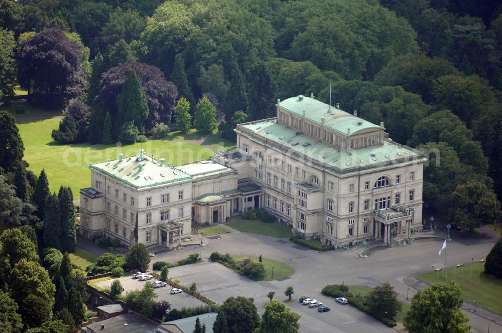 Aerial image ESSEN - Die Villa Hügel, im Essener Stadtteil Bredeney gelegen, wurde 1873 von Alfred Krupp errichtet und ist das ehemalige Wohn- und Repräsentationshaus der Industriellenfamilie Krupp. Die Villa hat 269 Räume, 8100 m² Wohn- und Nutzfläche und liegt in einem 28 Hektar großen Park an prominenter Stelle über dem Ruhrtal und dem Baldeneysee. Verwaltet wird sie heute durch die Kulturstiftung Ruhr, welche regelmäßig Veranstaltungen wie Konzerte oder Ausstellungen dort durchführt. Außerhalb dieser Zeiten kann sie in den Öffnungszeiten besichtigt werden.Die Entstehung der Villa Hügel geht einher mit den Veränderungen in der Friedrich Krupp AG. 1862 wurde durch Alfred Krupp die Prokura eingeführt. Er beabsichtigte damit seine Rolle in der stark gewachsenen Firma auf die strategischen Entscheidungen und die Aufsichtsfunktion zu beschränken. War es bis dato üblich, auf dem Firmengelände zu leben, spiegelt sich dieser „Rückzug“ auch in der Verlagerung des Wohnsitzes der Familie wieder. Im Herbst 1863 besichtigte Krupp das heutige Gelände der Villa und entschloss sich im Januar 1864 soviel wie möglich des damaligen Gutes Klosterbuschhof zu erwerben. Um den Umzug zu beschleunigen, wurde zunächst der Klosterbuschhof um einen Turm erweitert und zu einer Villa umgebaut. Erste Skizzen des Baues wurden von Krupp selbst entworfen und dem firmeninternen Baubüro, zunächst unter der Leitung von Ferdinand Barchewitz, ab 1863 unter der Leitung von Gustav Kraemer, zur weiteren Bearbeitung vorgelegt. Barchewitz fertigte, nachdem Kraemer die Leitung des Baubüros übernommen hatte, Pläne nach den Skizzen Krupps an, welche als Grundlage für die weiteren Planungen dienten. Über den ganzen Zeitraum hinweg unterstützte auch der aus Heinersdorf stammende Architekt Thomas Obstfelder die Arbeiten.1953 stellte die Familie Krupp ihren Wohnsitz für eine bedeutende Kunstausstellung zur Verfügung, die nicht die letzte bleiben sollte. Bis Ende der 90er fungierte die Villa Hügel auch als Repräsentationsgebäude der Firma ThyssenKrupp. 1984 rief man die Kulturstiftung Ruhr ins Leben, die regelmäßig Ausstellungen in der Villa Hügel organisiert. Im Nebengebäude ist das Krupp-Museum zur Firmengeschichte untergebracht.