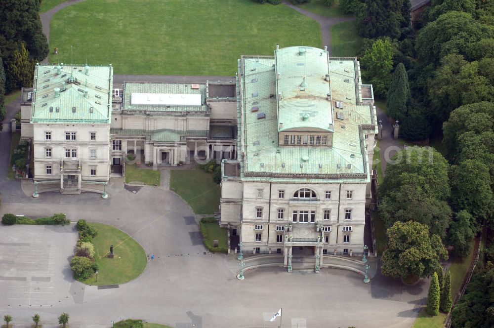 ESSEN from the bird's eye view: Die Villa Hügel, im Essener Stadtteil Bredeney gelegen, wurde 1873 von Alfred Krupp errichtet und ist das ehemalige Wohn- und Repräsentationshaus der Industriellenfamilie Krupp. Die Villa hat 269 Räume, 8100 m² Wohn- und Nutzfläche und liegt in einem 28 Hektar großen Park an prominenter Stelle über dem Ruhrtal und dem Baldeneysee. Verwaltet wird sie heute durch die Kulturstiftung Ruhr, welche regelmäßig Veranstaltungen wie Konzerte oder Ausstellungen dort durchführt. Außerhalb dieser Zeiten kann sie in den Öffnungszeiten besichtigt werden.Die Entstehung der Villa Hügel geht einher mit den Veränderungen in der Friedrich Krupp AG. 1862 wurde durch Alfred Krupp die Prokura eingeführt. Er beabsichtigte damit seine Rolle in der stark gewachsenen Firma auf die strategischen Entscheidungen und die Aufsichtsfunktion zu beschränken. War es bis dato üblich, auf dem Firmengelände zu leben, spiegelt sich dieser „Rückzug“ auch in der Verlagerung des Wohnsitzes der Familie wieder. Im Herbst 1863 besichtigte Krupp das heutige Gelände der Villa und entschloss sich im Januar 1864 soviel wie möglich des damaligen Gutes Klosterbuschhof zu erwerben. Um den Umzug zu beschleunigen, wurde zunächst der Klosterbuschhof um einen Turm erweitert und zu einer Villa umgebaut. Erste Skizzen des Baues wurden von Krupp selbst entworfen und dem firmeninternen Baubüro, zunächst unter der Leitung von Ferdinand Barchewitz, ab 1863 unter der Leitung von Gustav Kraemer, zur weiteren Bearbeitung vorgelegt. Barchewitz fertigte, nachdem Kraemer die Leitung des Baubüros übernommen hatte, Pläne nach den Skizzen Krupps an, welche als Grundlage für die weiteren Planungen dienten. Über den ganzen Zeitraum hinweg unterstützte auch der aus Heinersdorf stammende Architekt Thomas Obstfelder die Arbeiten.1953 stellte die Familie Krupp ihren Wohnsitz für eine bedeutende Kunstausstellung zur Verfügung, die nicht die letzte bleiben sollte. Bis Ende der 90er fungierte die Villa Hügel auch als Repräsentationsgebäude der Firma ThyssenKrupp. 1984 rief man die Kulturstiftung Ruhr ins Leben, die regelmäßig Ausstellungen in der Villa Hügel organisiert. Im Nebengebäude ist das Krupp-Museum zur Firmengeschichte untergebracht.