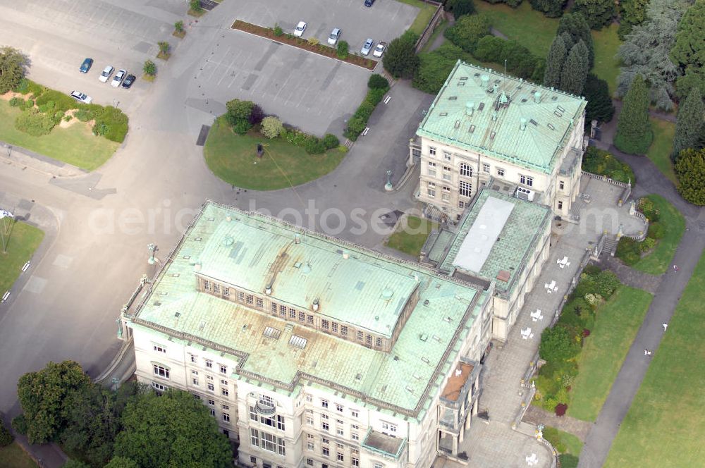 Aerial image ESSEN - Die Villa Hügel, im Essener Stadtteil Bredeney gelegen, wurde 1873 von Alfred Krupp errichtet und ist das ehemalige Wohn- und Repräsentationshaus der Industriellenfamilie Krupp. Die Villa hat 269 Räume, 8100 m² Wohn- und Nutzfläche und liegt in einem 28 Hektar großen Park an prominenter Stelle über dem Ruhrtal und dem Baldeneysee. Verwaltet wird sie heute durch die Kulturstiftung Ruhr, welche regelmäßig Veranstaltungen wie Konzerte oder Ausstellungen dort durchführt. Außerhalb dieser Zeiten kann sie in den Öffnungszeiten besichtigt werden.Die Entstehung der Villa Hügel geht einher mit den Veränderungen in der Friedrich Krupp AG. 1862 wurde durch Alfred Krupp die Prokura eingeführt. Er beabsichtigte damit seine Rolle in der stark gewachsenen Firma auf die strategischen Entscheidungen und die Aufsichtsfunktion zu beschränken. War es bis dato üblich, auf dem Firmengelände zu leben, spiegelt sich dieser „Rückzug“ auch in der Verlagerung des Wohnsitzes der Familie wieder. Im Herbst 1863 besichtigte Krupp das heutige Gelände der Villa und entschloss sich im Januar 1864 soviel wie möglich des damaligen Gutes Klosterbuschhof zu erwerben. Um den Umzug zu beschleunigen, wurde zunächst der Klosterbuschhof um einen Turm erweitert und zu einer Villa umgebaut. Erste Skizzen des Baues wurden von Krupp selbst entworfen und dem firmeninternen Baubüro, zunächst unter der Leitung von Ferdinand Barchewitz, ab 1863 unter der Leitung von Gustav Kraemer, zur weiteren Bearbeitung vorgelegt. Barchewitz fertigte, nachdem Kraemer die Leitung des Baubüros übernommen hatte, Pläne nach den Skizzen Krupps an, welche als Grundlage für die weiteren Planungen dienten. Über den ganzen Zeitraum hinweg unterstützte auch der aus Heinersdorf stammende Architekt Thomas Obstfelder die Arbeiten.1953 stellte die Familie Krupp ihren Wohnsitz für eine bedeutende Kunstausstellung zur Verfügung, die nicht die letzte bleiben sollte. Bis Ende der 90er fungierte die Villa Hügel auch als Repräsentationsgebäude der Firma ThyssenKrupp. 1984 rief man die Kulturstiftung Ruhr ins Leben, die regelmäßig Ausstellungen in der Villa Hügel organisiert. Im Nebengebäude ist das Krupp-Museum zur Firmengeschichte untergebracht.