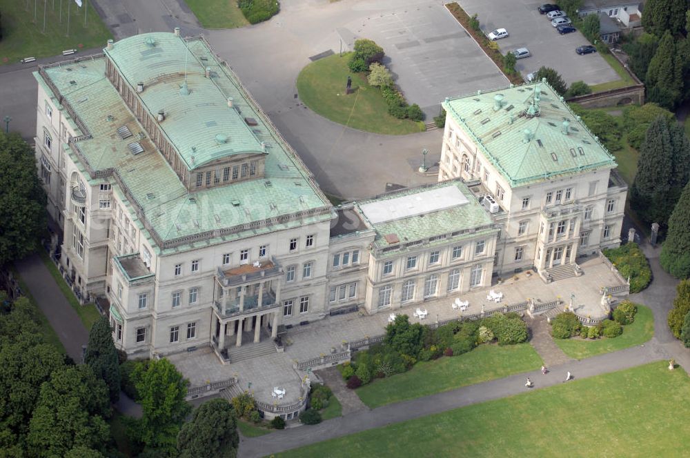 ESSEN from above - Die Villa Hügel, im Essener Stadtteil Bredeney gelegen, wurde 1873 von Alfred Krupp errichtet und ist das ehemalige Wohn- und Repräsentationshaus der Industriellenfamilie Krupp. Die Villa hat 269 Räume, 8100 m² Wohn- und Nutzfläche und liegt in einem 28 Hektar großen Park an prominenter Stelle über dem Ruhrtal und dem Baldeneysee. Verwaltet wird sie heute durch die Kulturstiftung Ruhr, welche regelmäßig Veranstaltungen wie Konzerte oder Ausstellungen dort durchführt. Außerhalb dieser Zeiten kann sie in den Öffnungszeiten besichtigt werden.Die Entstehung der Villa Hügel geht einher mit den Veränderungen in der Friedrich Krupp AG. 1862 wurde durch Alfred Krupp die Prokura eingeführt. Er beabsichtigte damit seine Rolle in der stark gewachsenen Firma auf die strategischen Entscheidungen und die Aufsichtsfunktion zu beschränken. War es bis dato üblich, auf dem Firmengelände zu leben, spiegelt sich dieser „Rückzug“ auch in der Verlagerung des Wohnsitzes der Familie wieder. Im Herbst 1863 besichtigte Krupp das heutige Gelände der Villa und entschloss sich im Januar 1864 soviel wie möglich des damaligen Gutes Klosterbuschhof zu erwerben. Um den Umzug zu beschleunigen, wurde zunächst der Klosterbuschhof um einen Turm erweitert und zu einer Villa umgebaut. Erste Skizzen des Baues wurden von Krupp selbst entworfen und dem firmeninternen Baubüro, zunächst unter der Leitung von Ferdinand Barchewitz, ab 1863 unter der Leitung von Gustav Kraemer, zur weiteren Bearbeitung vorgelegt. Barchewitz fertigte, nachdem Kraemer die Leitung des Baubüros übernommen hatte, Pläne nach den Skizzen Krupps an, welche als Grundlage für die weiteren Planungen dienten. Über den ganzen Zeitraum hinweg unterstützte auch der aus Heinersdorf stammende Architekt Thomas Obstfelder die Arbeiten.1953 stellte die Familie Krupp ihren Wohnsitz für eine bedeutende Kunstausstellung zur Verfügung, die nicht die letzte bleiben sollte. Bis Ende der 90er fungierte die Villa Hügel auch als Repräsentationsgebäude der Firma ThyssenKrupp. 1984 rief man die Kulturstiftung Ruhr ins Leben, die regelmäßig Ausstellungen in der Villa Hügel organisiert. Im Nebengebäude ist das Krupp-Museum zur Firmengeschichte untergebracht.