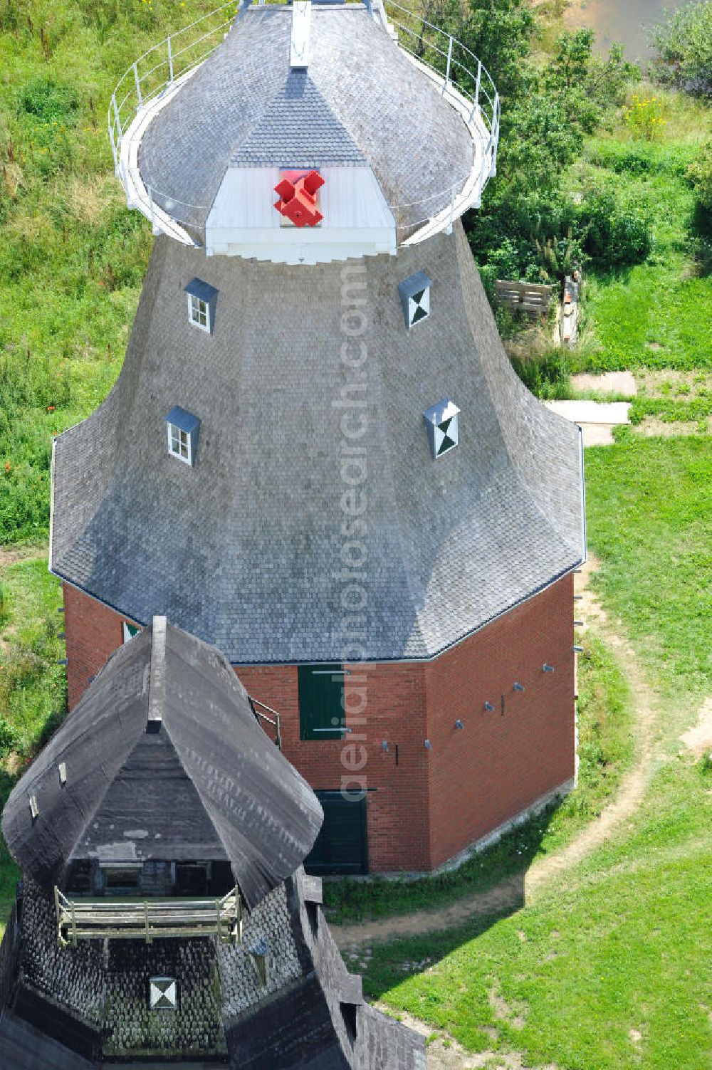 Aerial photograph Neu Vorwerk - Blick auf die Zwillingsmühlen von Neu Vorwerk in Mecklenburg-Vorpommern. Bei diesem einzigartigen technischen Denkmal auf dem Mühlenberg zwischen Neu Vorwerk und Alt Vorwerk präsentieren sich dem Besucher zwei Windmühlen als Wahrzeichen nebeneinan der. 1847 kam es zur Errichtung des Erdholländers auf dem Gut Alt Vorwerk. 1949 kam es zum Neubau des großes Galerieholländers. Er stellt wohl den letzten Windmühlenneubau Deutschlands dar. Twin Mills of New Vorwerk.