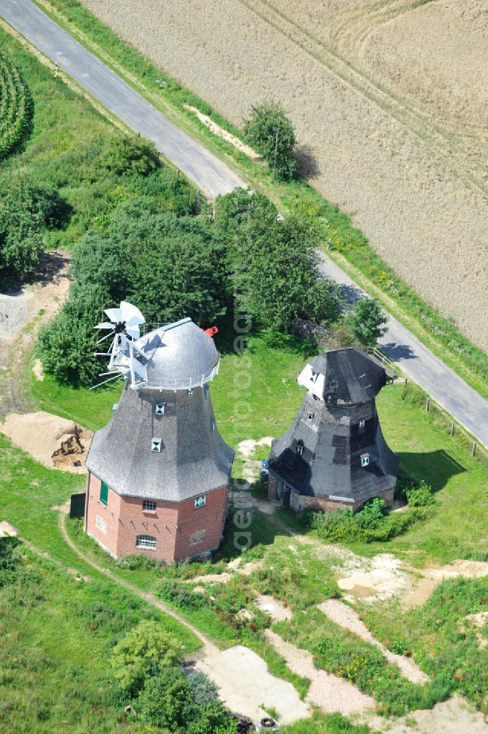 Aerial photograph Neu Vorwerk - Blick auf die Zwillingsmühlen von Neu Vorwerk in Mecklenburg-Vorpommern. Bei diesem einzigartigen technischen Denkmal auf dem Mühlenberg zwischen Neu Vorwerk und Alt Vorwerk präsentieren sich dem Besucher zwei Windmühlen als Wahrzeichen nebeneinan der. 1847 kam es zur Errichtung des Erdholländers auf dem Gut Alt Vorwerk. 1949 kam es zum Neubau des großes Galerieholländers. Er stellt wohl den letzten Windmühlenneubau Deutschlands dar. Twin Mills of New Vorwerk.