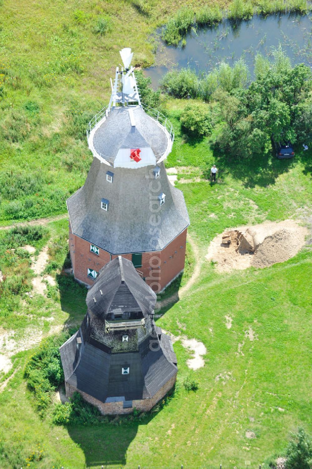 Aerial photograph Neu Vorwerk - Blick auf die Zwillingsmühlen von Neu Vorwerk in Mecklenburg-Vorpommern. Bei diesem einzigartigen technischen Denkmal auf dem Mühlenberg zwischen Neu Vorwerk und Alt Vorwerk präsentieren sich dem Besucher zwei Windmühlen als Wahrzeichen nebeneinan der. 1847 kam es zur Errichtung des Erdholländers auf dem Gut Alt Vorwerk. 1949 kam es zum Neubau des großes Galerieholländers. Er stellt wohl den letzten Windmühlenneubau Deutschlands dar. Twin Mills of New Vorwerk.