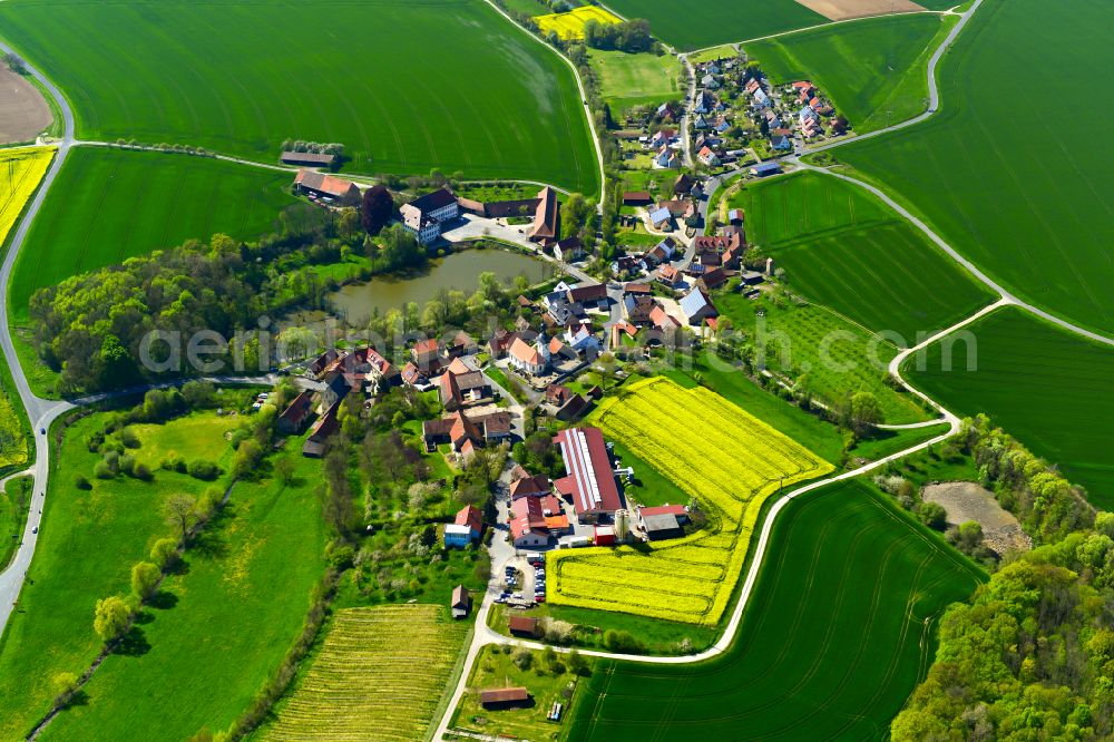 Bimbach from above - Agricultural land and field boundaries surround the settlement area of the village in Bimbach in the state Bavaria, Germany