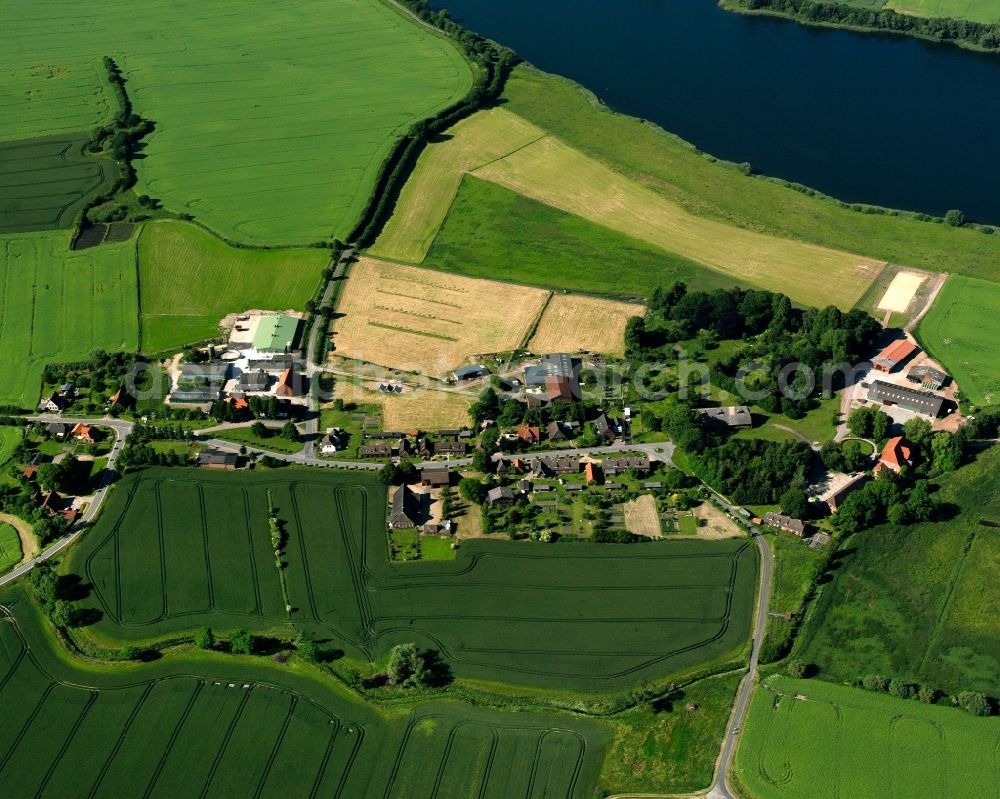 Farchauer Mühle from above - Agricultural land and field boundaries surround the settlement area of the village in Farchauer Mühle in the state Schleswig-Holstein, Germany