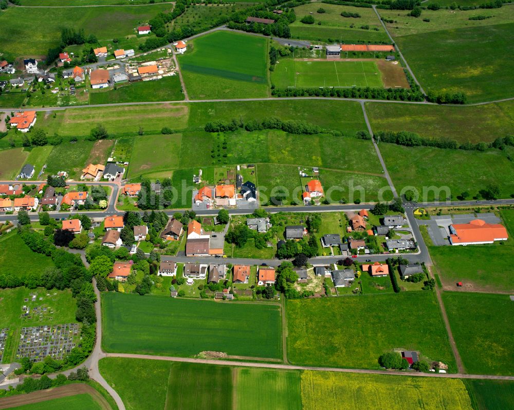 Freiensteinau from the bird's eye view: Agricultural land and field boundaries surround the settlement area of the village in Freiensteinau in the state Hesse, Germany