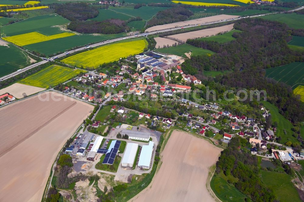 Gröditz from the bird's eye view: Agricultural land and field boundaries surround the settlement area of the village in Groeditz in the state Saxony, Germany