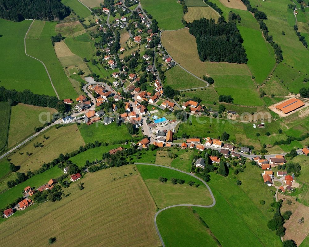 Güttersbach from above - Agricultural land and field boundaries surround the settlement area of the village in Güttersbach in the state Hesse, Germany