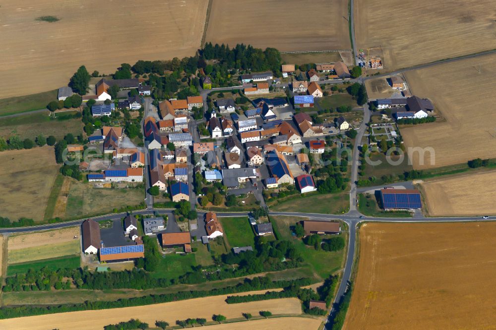 Aerial image Gützingen - Agricultural land and field boundaries surround the settlement area of the village in Gützingen in the state Bavaria, Germany