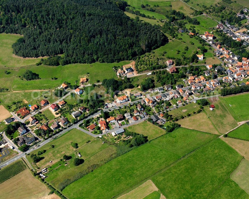 Hainstadt from above - Agricultural land and field boundaries surround the settlement area of the village in Hainstadt in the state Hesse, Germany