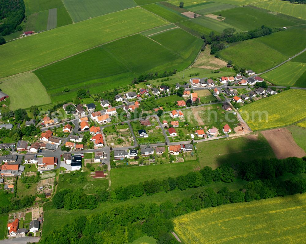 Hattendorf from the bird's eye view: Agricultural land and field boundaries surround the settlement area of the village in Hattendorf in the state Hesse, Germany