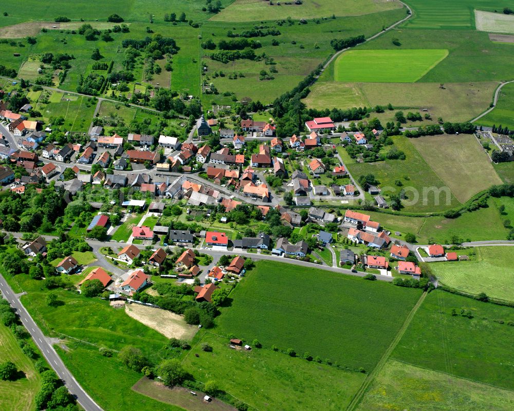 Helpershain from above - Agricultural land and field boundaries surround the settlement area of the village in Helpershain in the state Hesse, Germany