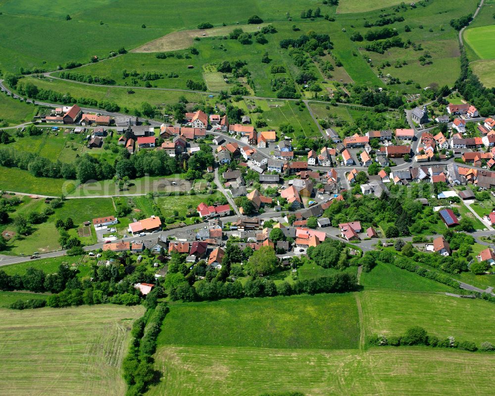 Helpershain from the bird's eye view: Agricultural land and field boundaries surround the settlement area of the village in Helpershain in the state Hesse, Germany