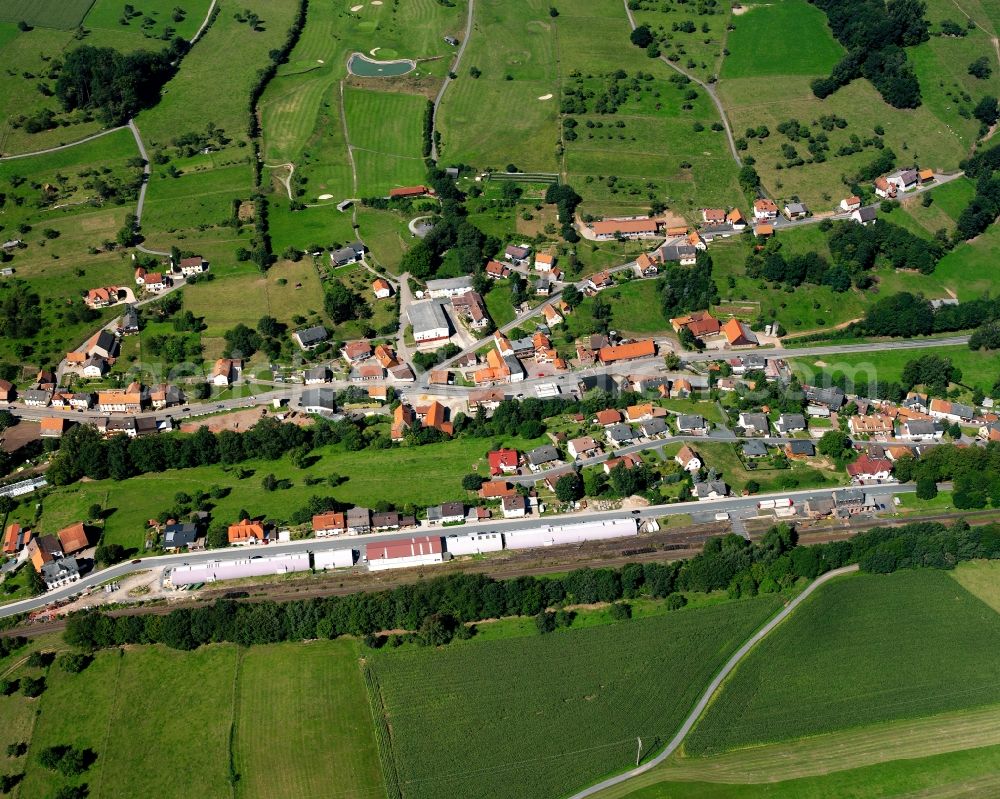 Hetzbach from the bird's eye view: Agricultural land and field boundaries surround the settlement area of the village in Hetzbach in the state Hesse, Germany