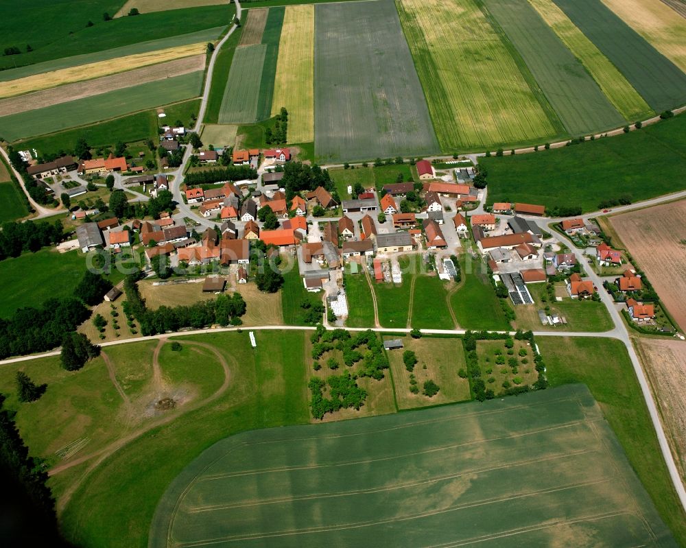 Heuberg from above - Agricultural land and field boundaries surround the settlement area of the village in Heuberg in the state Bavaria, Germany