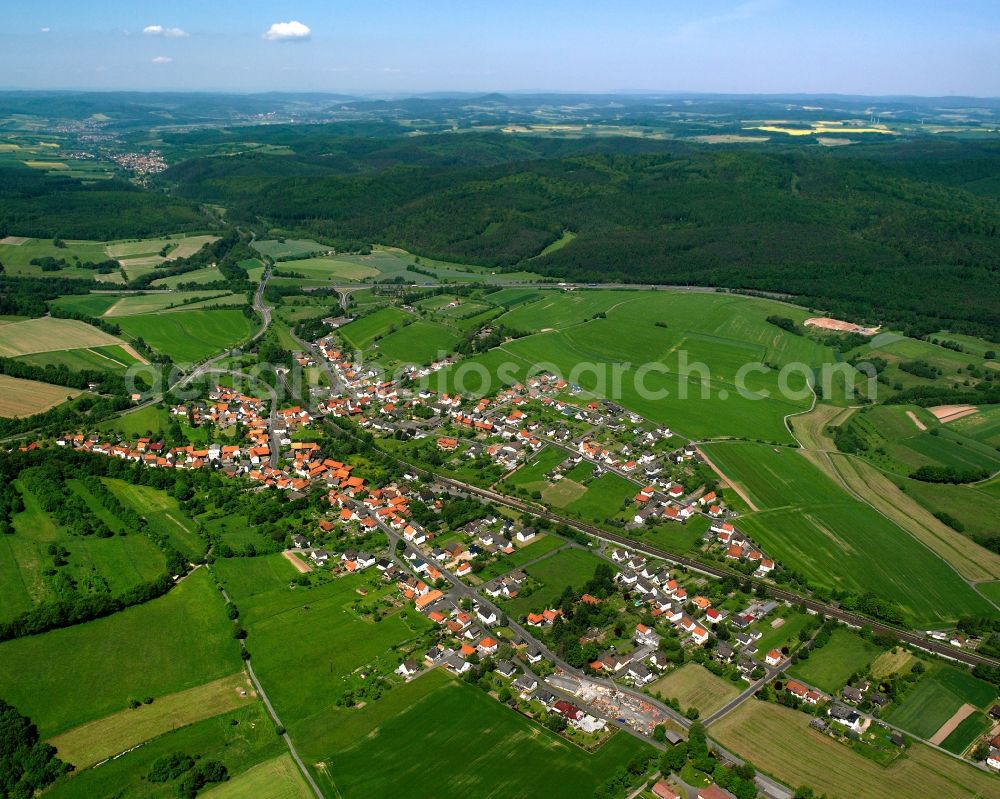 Aerial photograph Hönebach - Agricultural land and field boundaries surround the settlement area of the village in Hönebach in the state Hesse, Germany