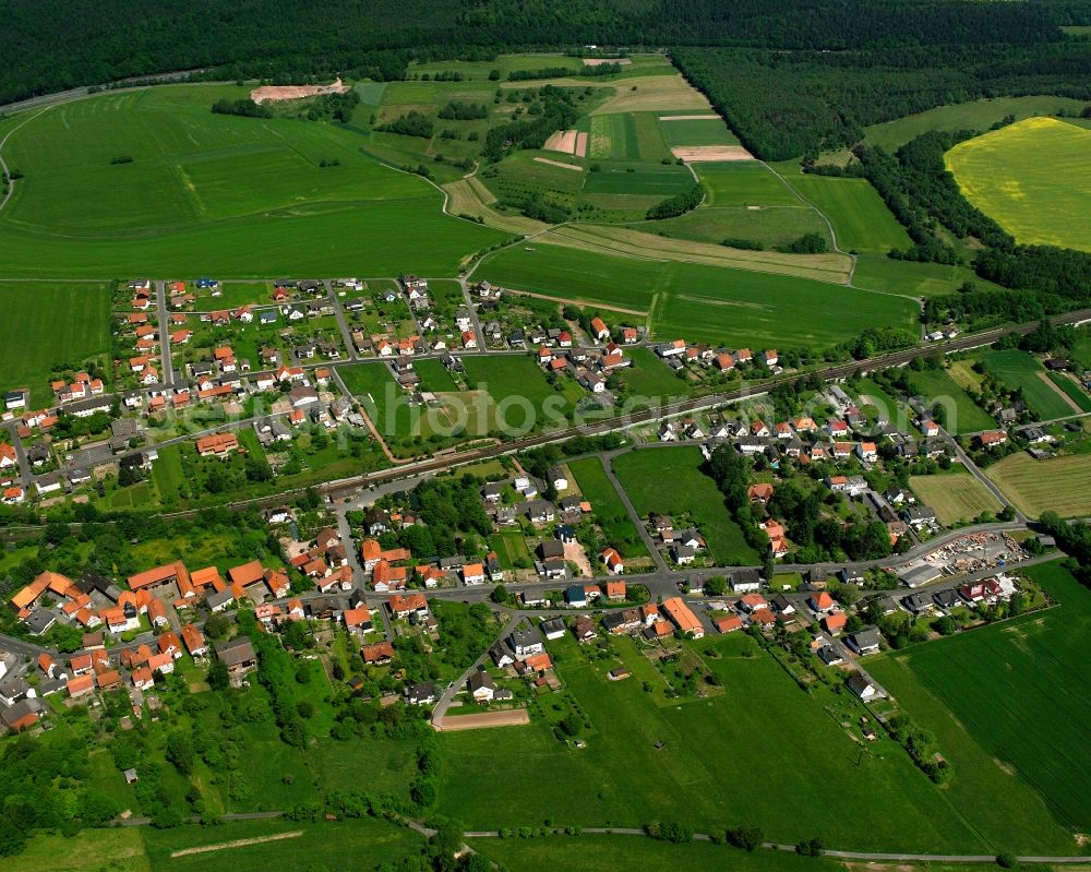 Hönebach from above - Agricultural land and field boundaries surround the settlement area of the village in Hönebach in the state Hesse, Germany