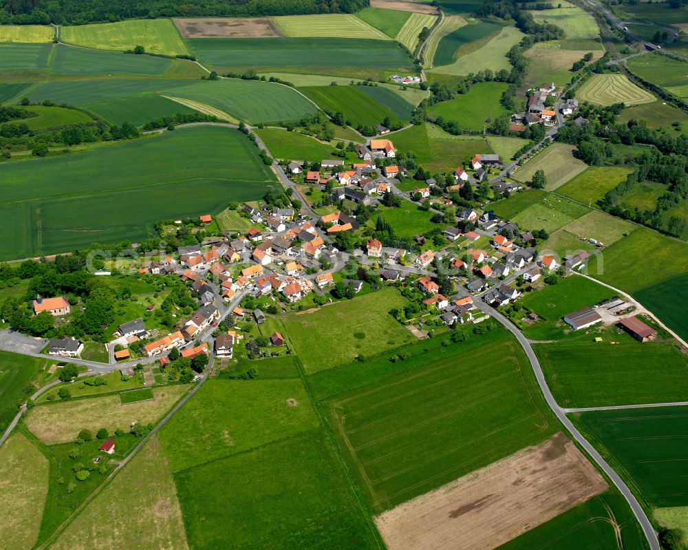 Hopfgarten from the bird's eye view: Agricultural land and field boundaries surround the settlement area of the village in Hopfgarten in the state Hesse, Germany