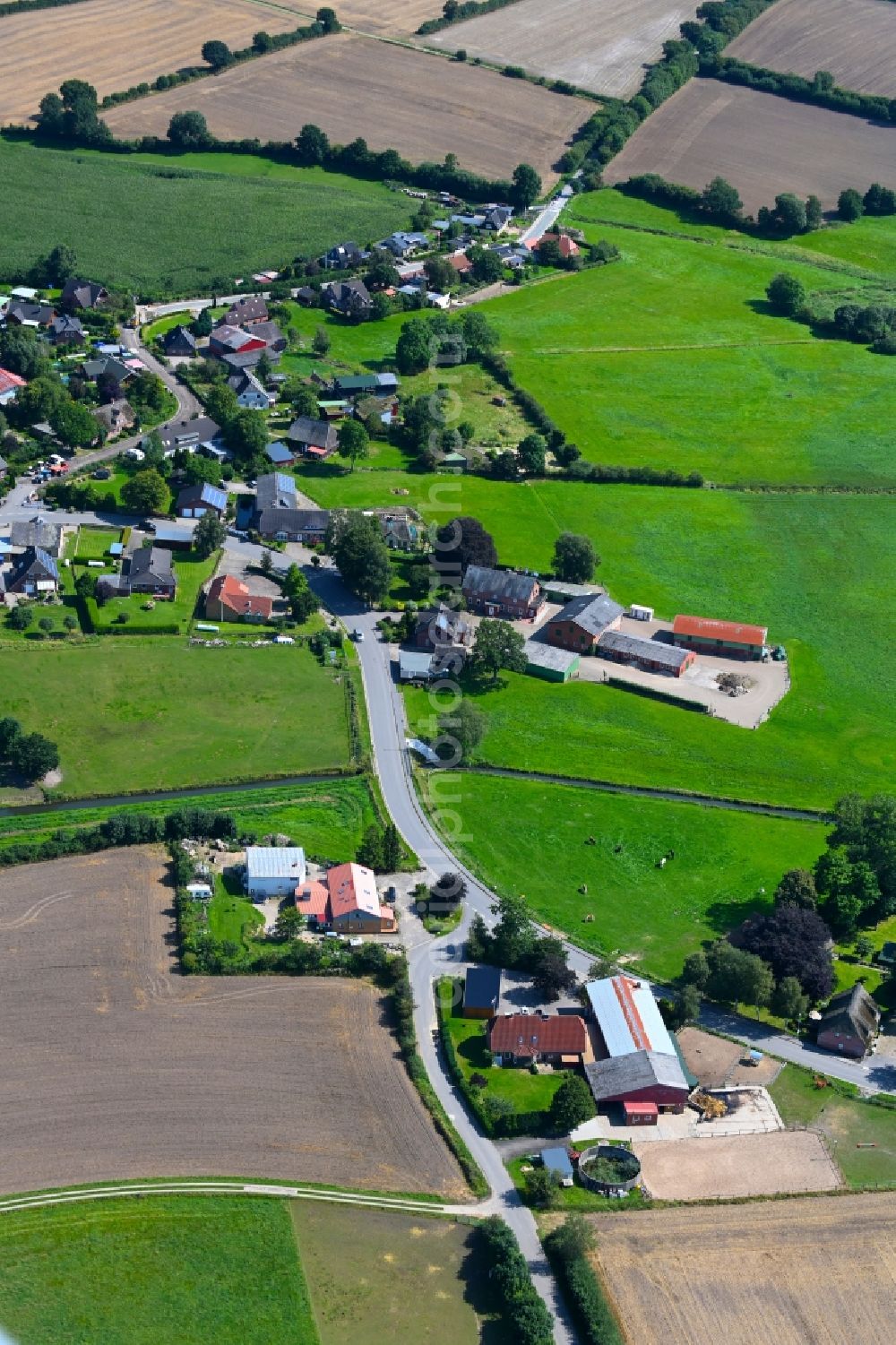 Hummelfeld from the bird's eye view: Agricultural land and field boundaries surround the settlement area of the village in Hummelfeld in the state Schleswig-Holstein, Germany