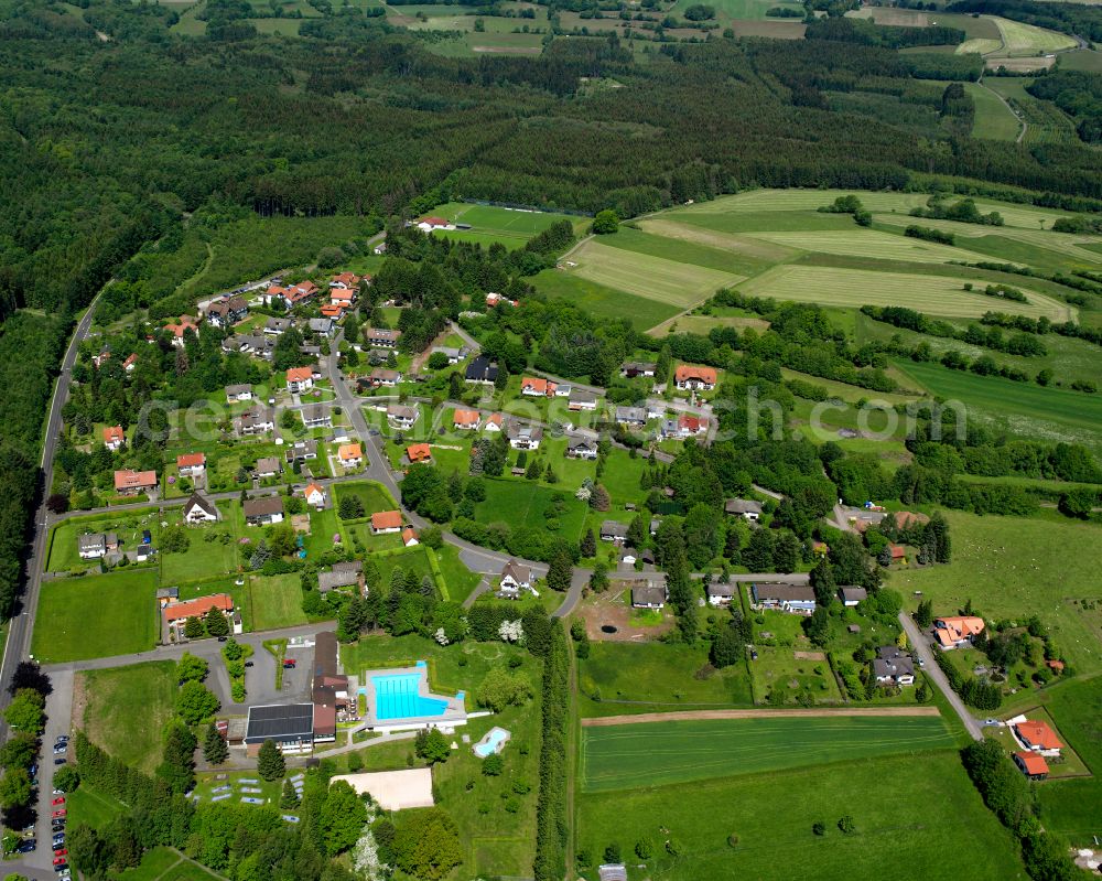 Aerial photograph Ilbeshausen-Hochwaldhausen - Agricultural land and field boundaries surround the settlement area of the village in Ilbeshausen-Hochwaldhausen in the state Hesse, Germany