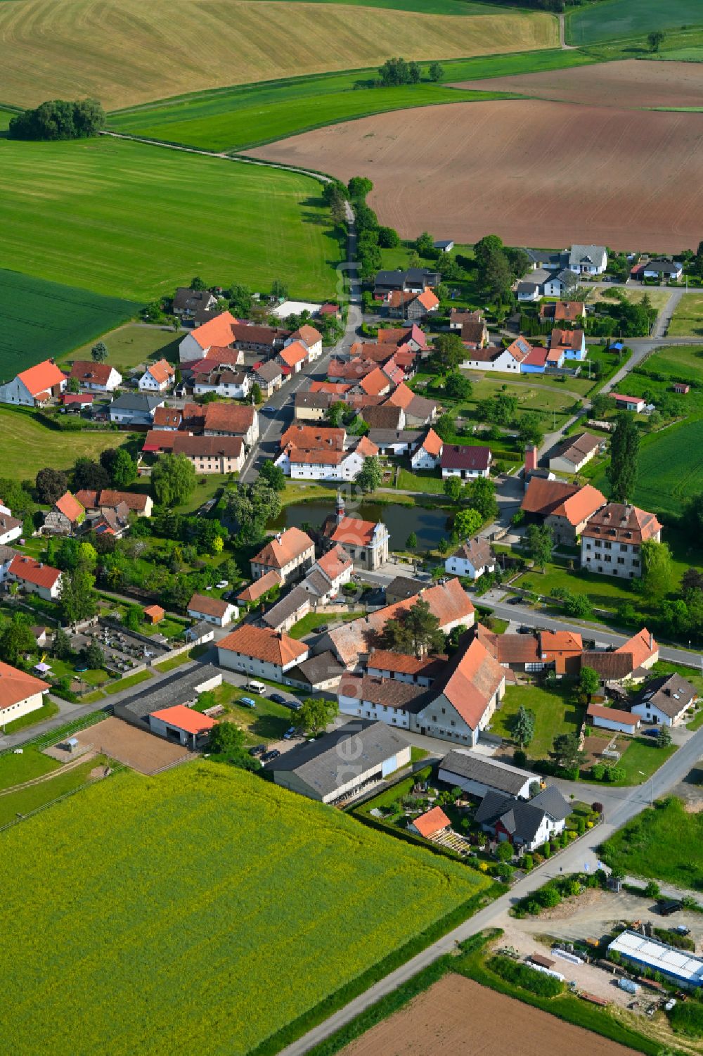 Leuzendorf i.UFr. from above - Agricultural land and field boundaries surround the settlement area of the village in Leuzendorf i.UFr. in the state Bavaria, Germany