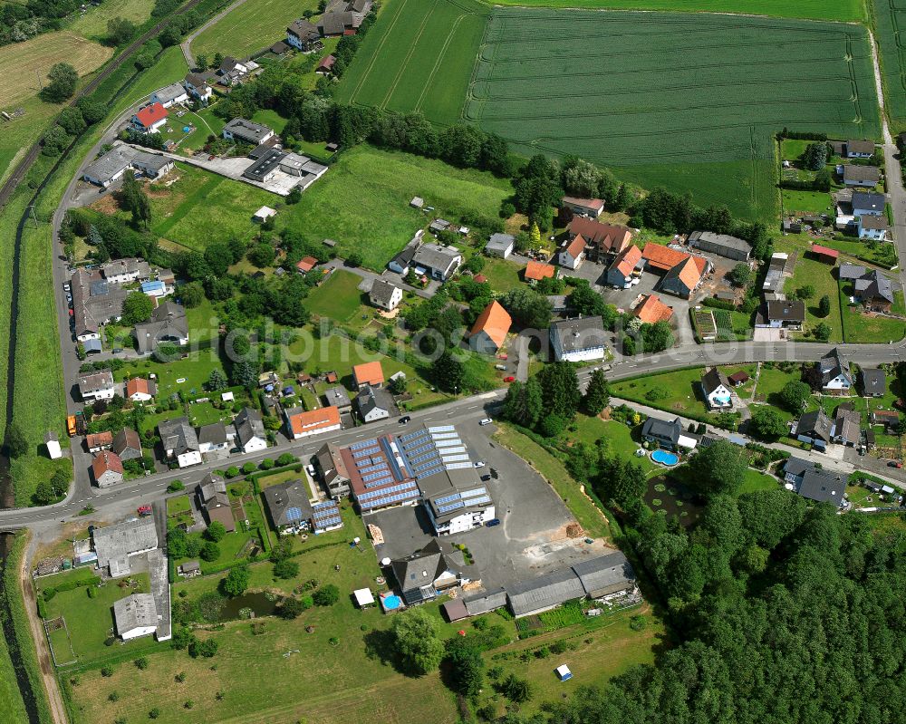 Merlau from above - Agricultural land and field boundaries surround the settlement area of the village in Merlau in the state Hesse, Germany