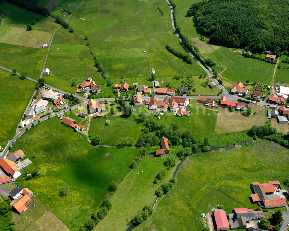 Radmühl from above - Agricultural land and field boundaries surround the settlement area of the village in Radmühl in the state Hesse, Germany