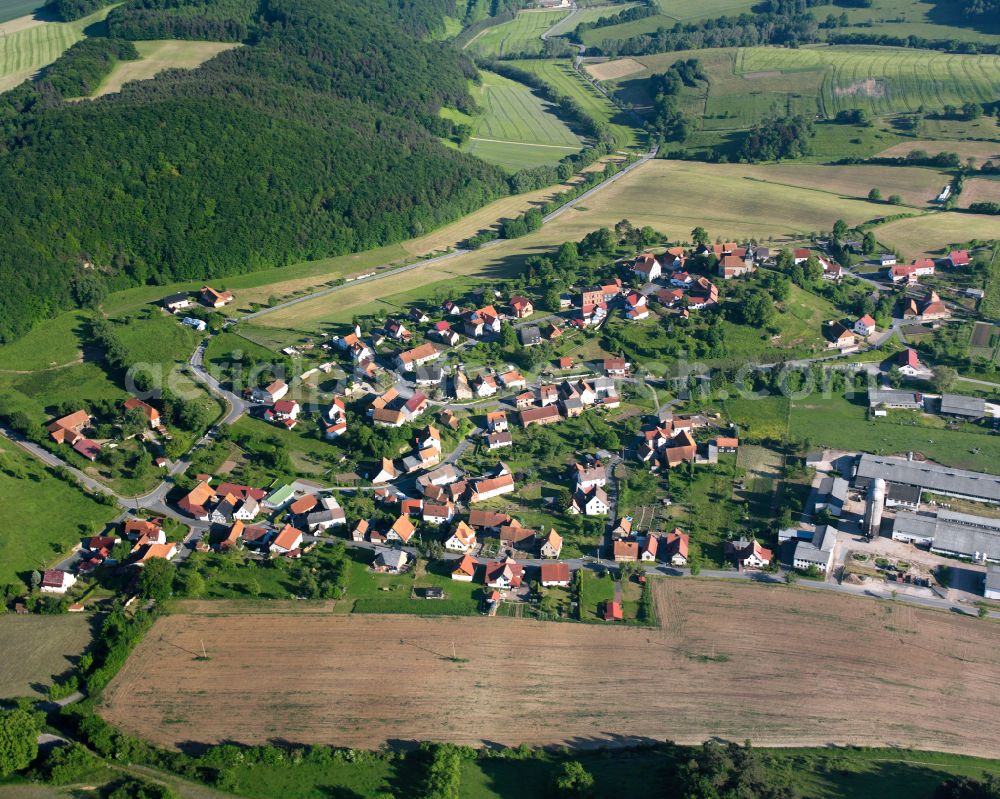 Aerial photograph Rüstungen - Agricultural land and field boundaries surround the settlement area of the village in Rüstungen in the state Thuringia, Germany