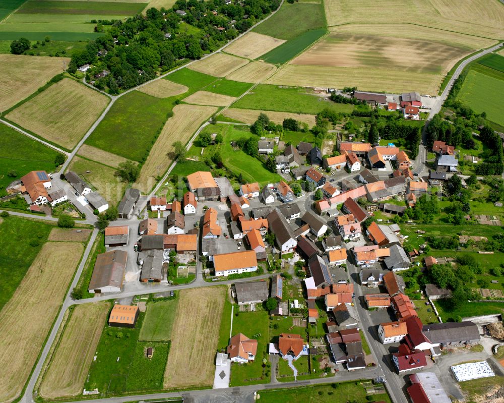 Schadenbach from above - Agricultural land and field boundaries surround the settlement area of the village in Schadenbach in the state Hesse, Germany