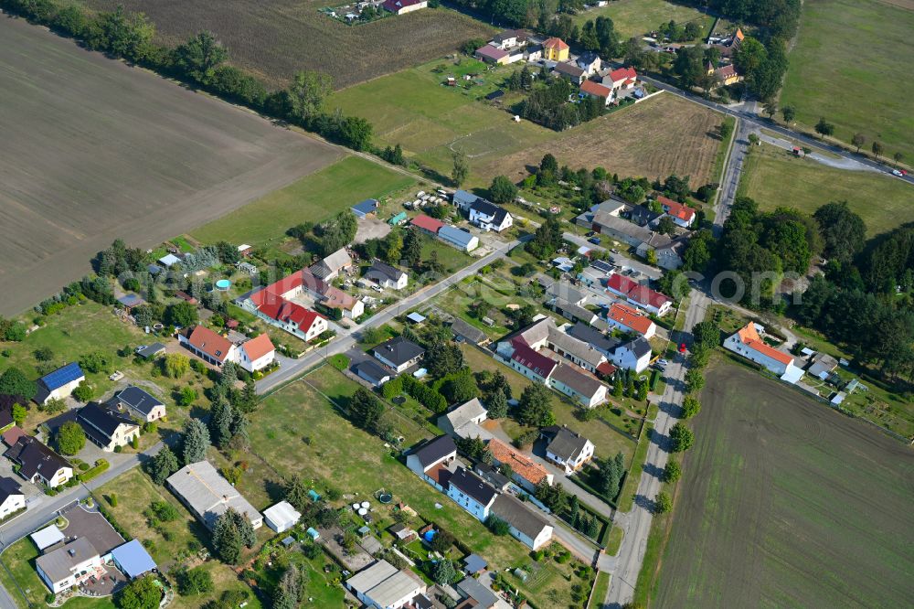 Schraden from above - Agricultural land and field boundaries surround the settlement area of the village on street Hauptstrasse in Schraden in the state Brandenburg, Germany