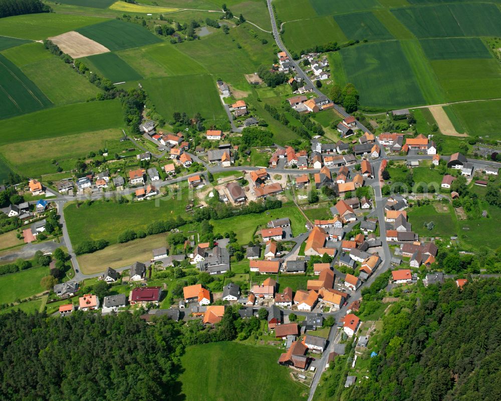 Udenhausen from above - Agricultural land and field boundaries surround the settlement area of the village in Udenhausen in the state Hesse, Germany