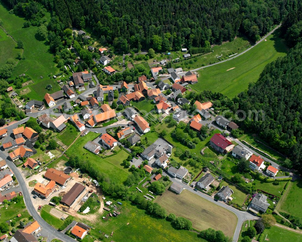 Udenhausen from the bird's eye view: Agricultural land and field boundaries surround the settlement area of the village in Udenhausen in the state Hesse, Germany