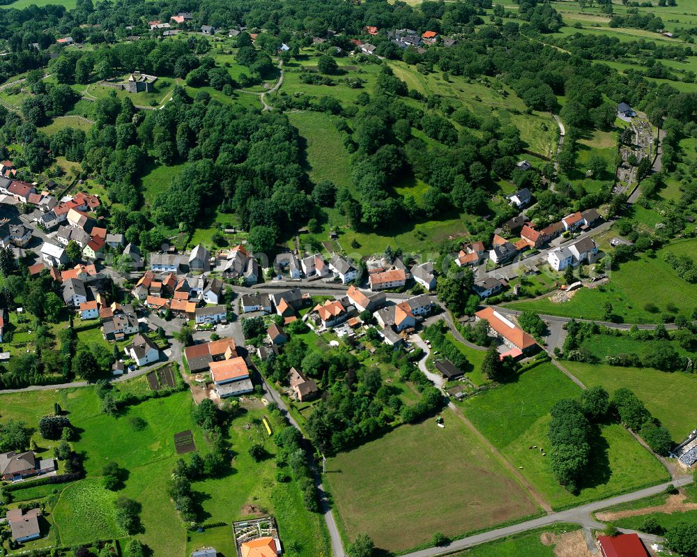 Ulrichstein from above - Agricultural land and field boundaries surround the settlement area of the village in Ulrichstein in the state Hesse, Germany