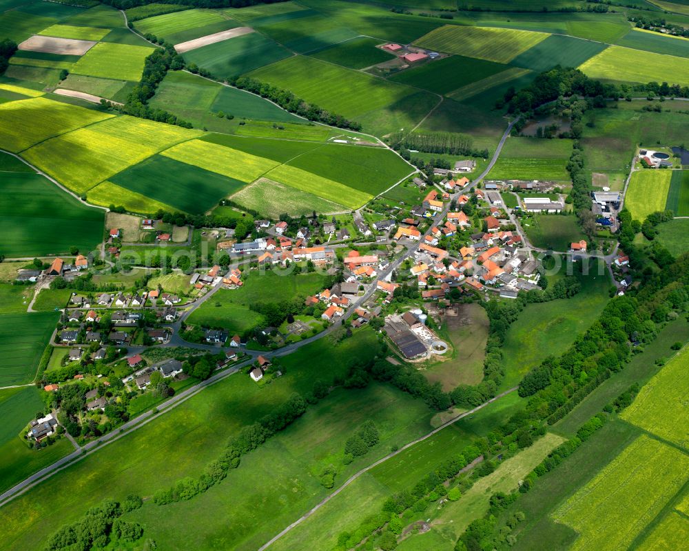 Wallersdorf from the bird's eye view: Agricultural land and field boundaries surround the settlement area of the village in Wallersdorf in the state Hesse, Germany