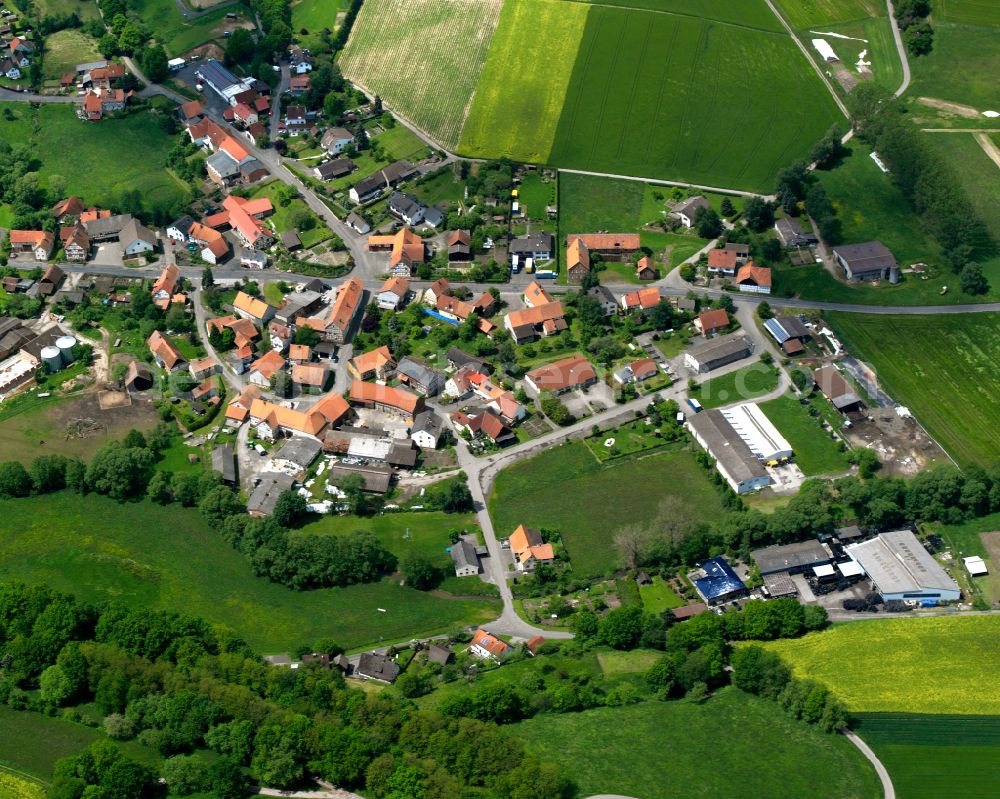 Wallersdorf from the bird's eye view: Agricultural land and field boundaries surround the settlement area of the village in Wallersdorf in the state Hesse, Germany