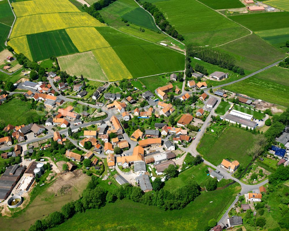 Wallersdorf from above - Agricultural land and field boundaries surround the settlement area of the village in Wallersdorf in the state Hesse, Germany