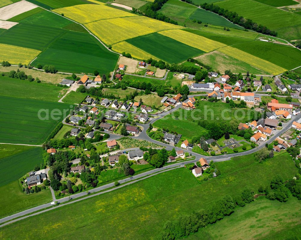 Wallersdorf from the bird's eye view: Agricultural land and field boundaries surround the settlement area of the village in Wallersdorf in the state Hesse, Germany