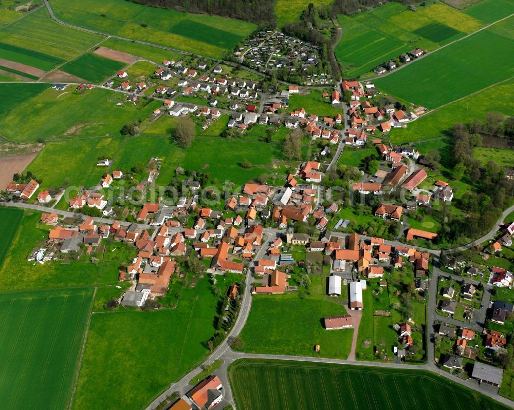 Wehrda from above - Agricultural land and field boundaries surround the settlement area of the village in Wehrda in the state Hesse, Germany